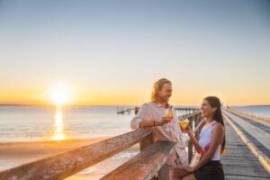 Couple sipping cocktails on pier at sunset on the Fraser Coast